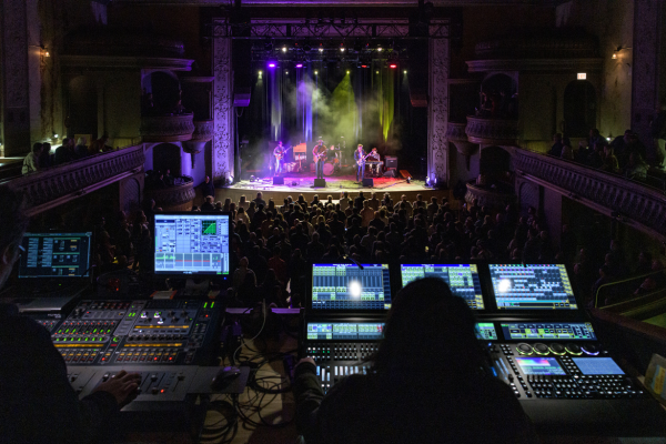 the light and sound tech working while looking out at ongoing concert on stage