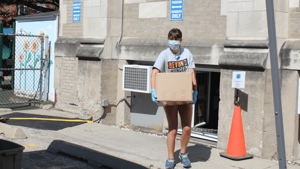 Beyond Hunger Volunteer carrying a box wearing a max for COVID-19