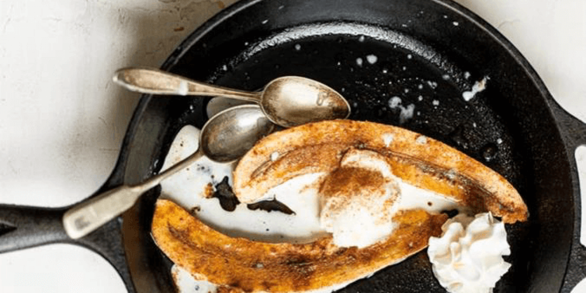 bananas with two vintage spoons in cast iron pan with whipped cream