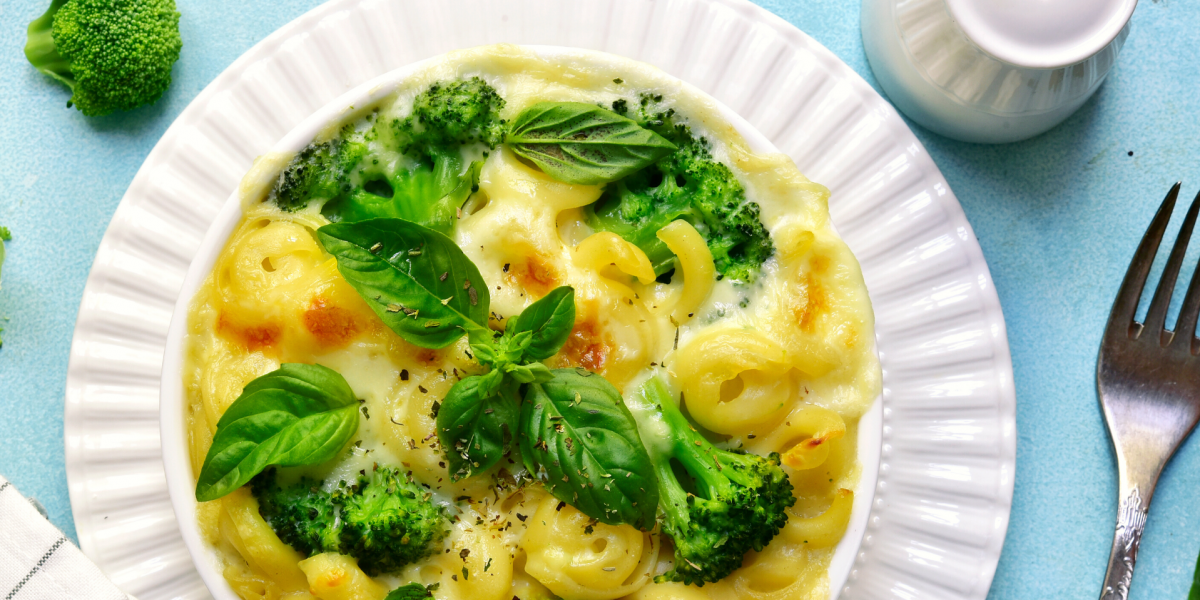 A plate of Baked Broccoli Mac and Cheese, on a white plate, against a blue background.