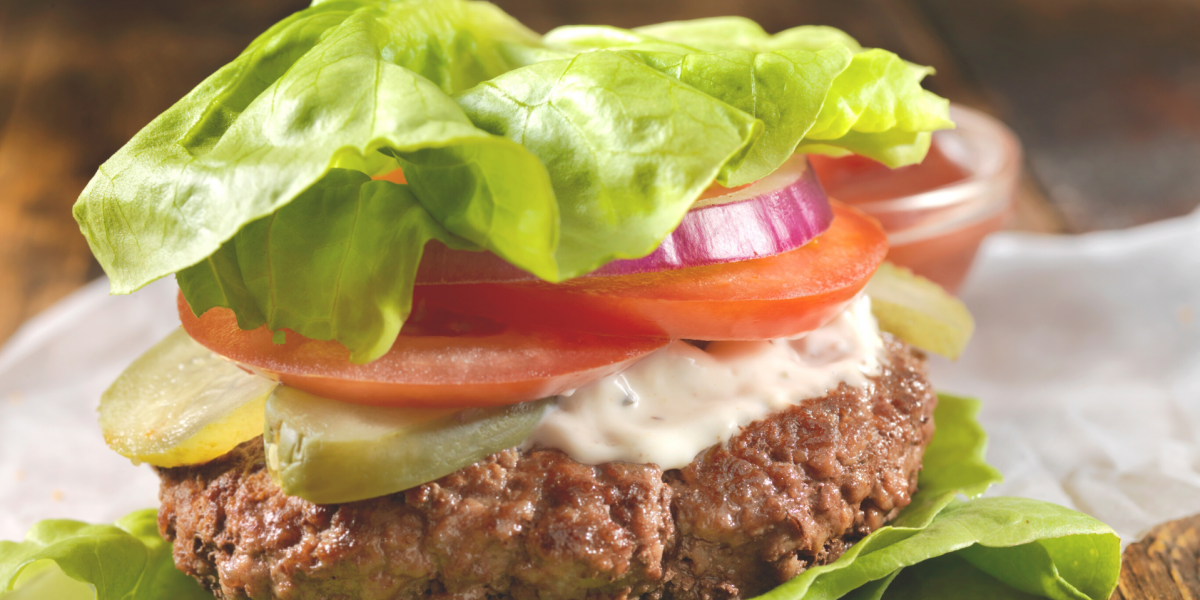 A classic California Style Burger, but wrapped in lettuce instead of a bun. Blurred and mostly white background.