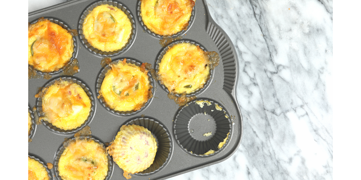 Holiday Brunch Cups in a cupcake-style baking pan. Food is yellow and orange, and background is grey granite.