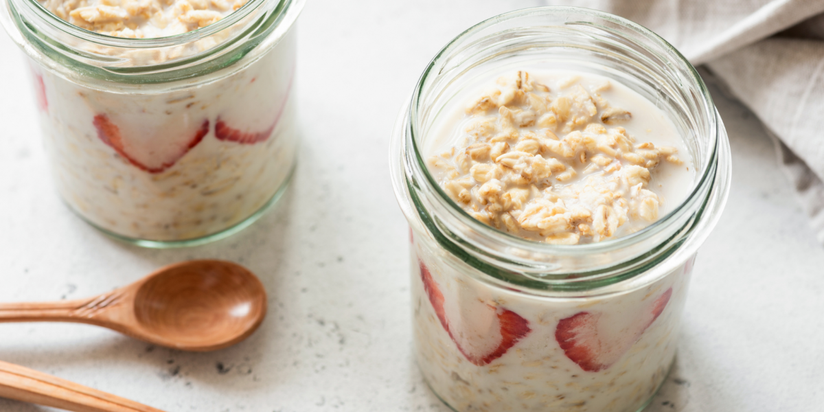 Two small mason jars full of overnight oatmeal, against a white background.