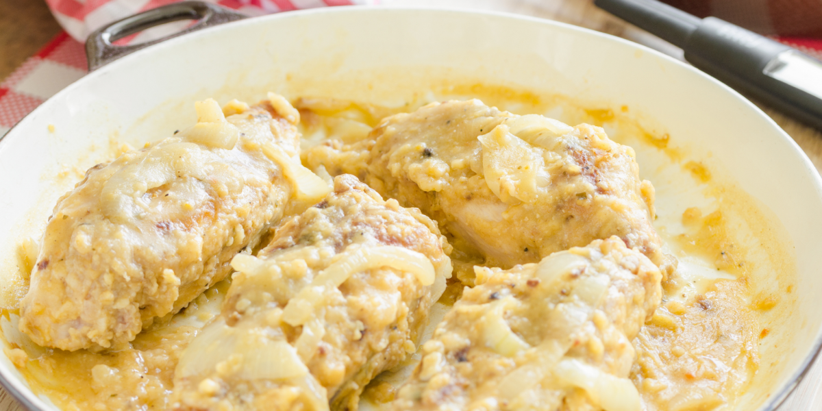 White pan full of smothered and covered chicken and gravy. Red plaid napkin is visible in the background.