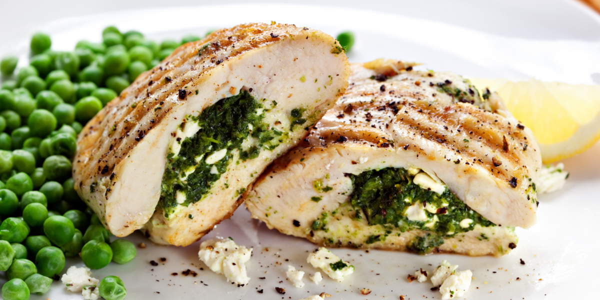 Spinach Stuffed Chicken Breasts with Tomato and Feta Recipe Photo. Grilled, stuffed chicken next to some peas, on a white plate.