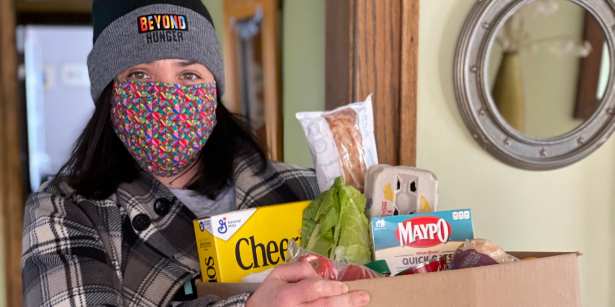 Woman in Beyond Hunger hat holding groceries