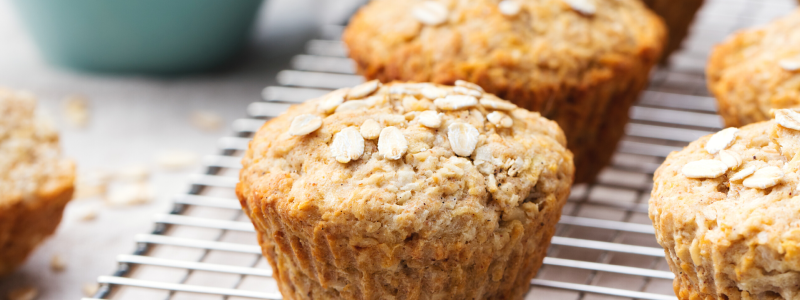 Photo of Apple Oatmeal Muffins on a metal cooling rack, with a blue bowl in the background.