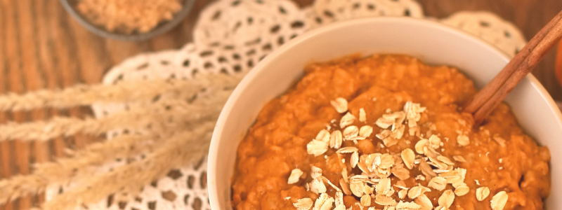 Photo of Baked Pumpkin Oatmeal in a white bowl, against an autumn themed background.
