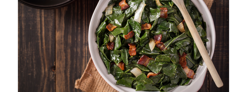 Braised greens in white bowl, with wooden spoon across the top of the dish.
