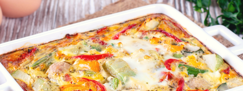 Hashbrown N' Peppers Casserole in a white baking dish, on a wooden counter.