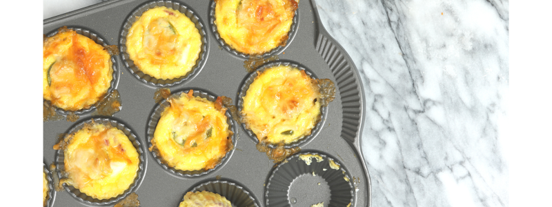 Holiday Brunch Cups in a cupcake-style baking pan. Food is yellow and orange, and background is grey granite.