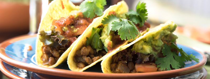 Lentil tacos on a plate, background of image is blurred.