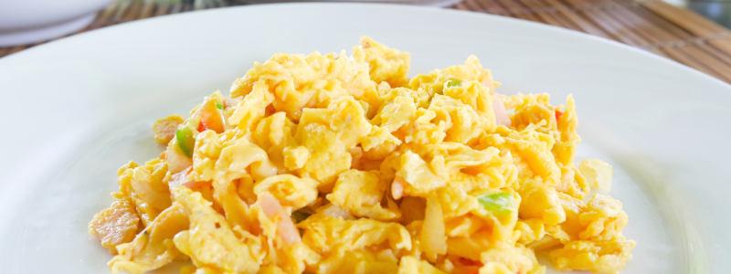 Microwave Breakfast Scramble Recipe Photo. White plate with scrambled eggs on it. Peppers and ham are mixed in with the eggs.