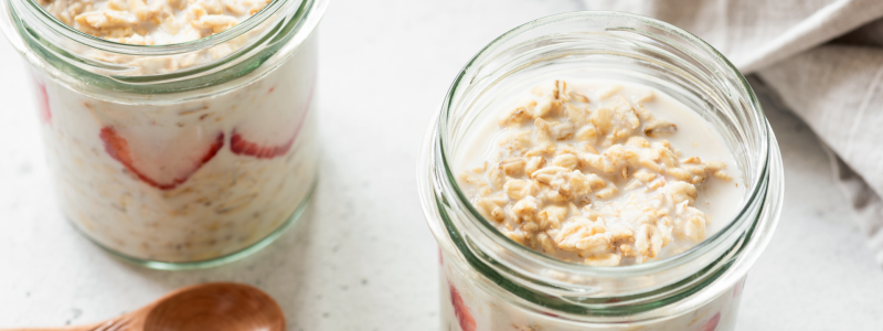 Two small mason jars full of overnight oatmeal, against a white background.