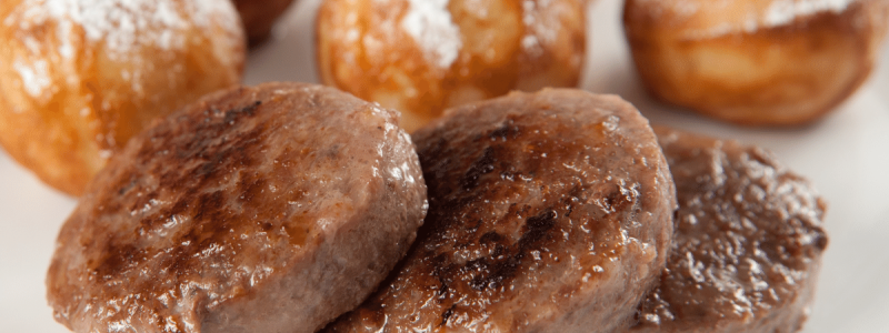 turkey breakfast sausage patties on white plate with beignets pictured in the background
