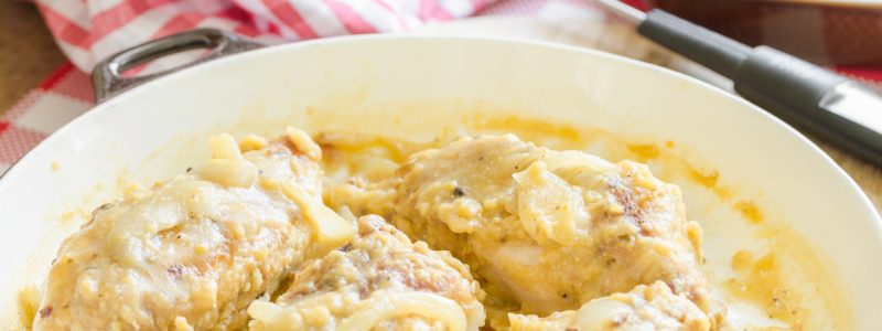 White pan full of smothered and covered chicken and gravy. Red plaid napkin is visible in the background.