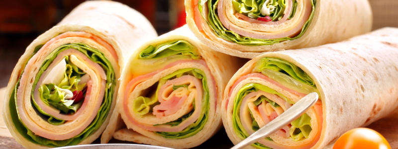 Four Turkey Tortilla Rollups stacked together in a sort of pile, on a cutting board.