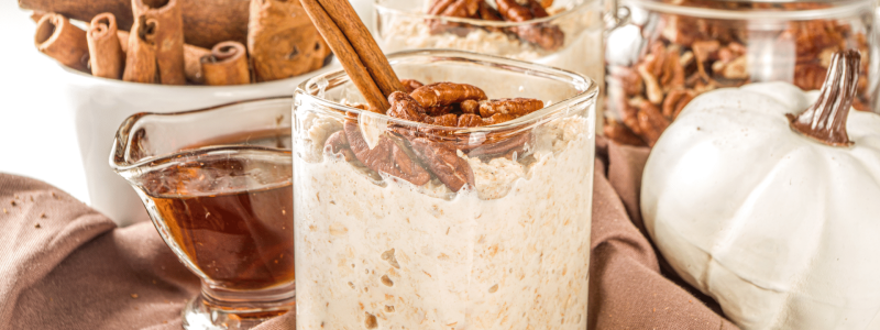 overnight oats with cinnamon and pecan garnish maple syrup in background