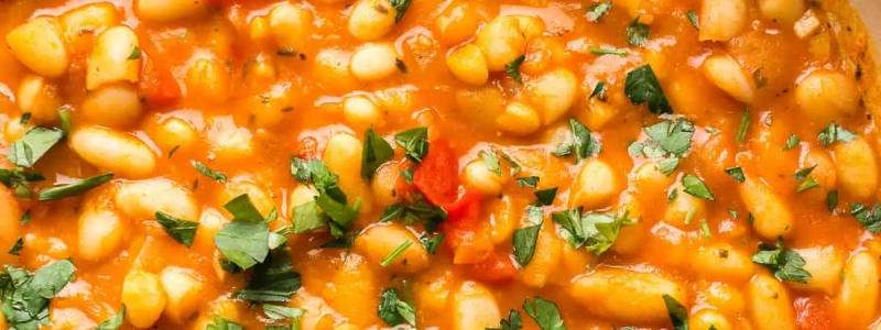 White bean stew in a ceramic pot with a wooden spoon stirring