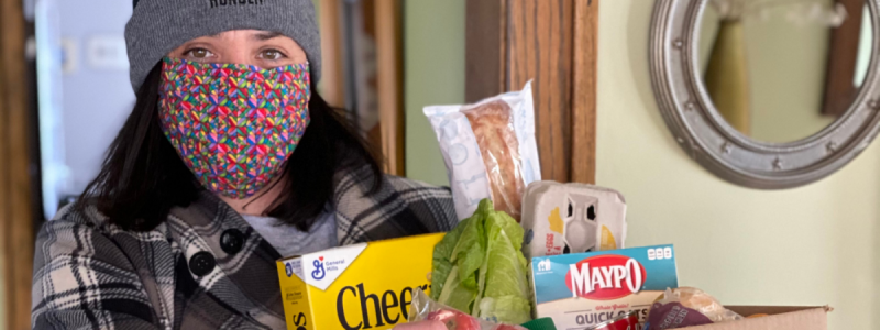 Woman in Beyond Hunger hat holding groceries