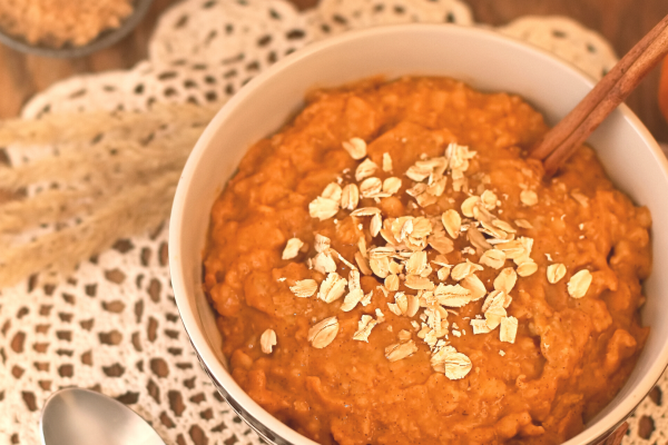 Photo of Baked Pumpkin Oatmeal in a white bowl, against an autumn themed background.