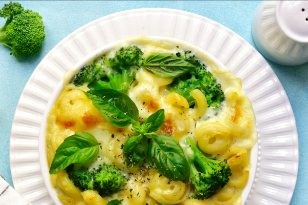 A plate of Baked Broccoli Mac and Cheese, on a white plate, against a blue background.