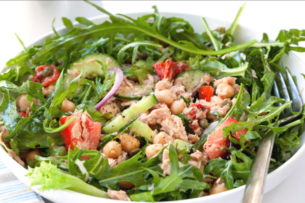 Chickpea Tuna Salad in a white bowl, against a white background. Salad also contains greens, tomatoes and other vegetables.