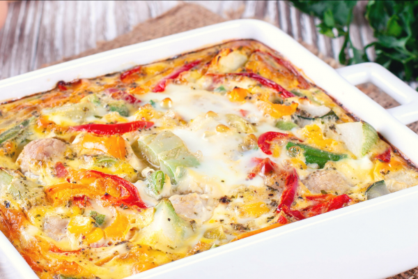 Hashbrown N' Peppers Casserole in a white baking dish, on a wooden counter.