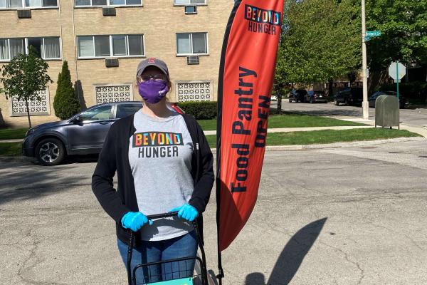 Carnival Cares - Shopping Cart and Katie Kearns near the Beyond Hunger flag