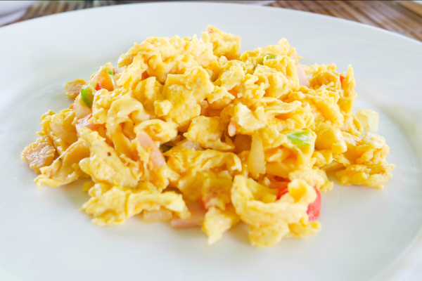 Microwave Breakfast Scramble Recipe Photo. White plate with scrambled eggs on it. Peppers and ham are mixed in with the eggs.