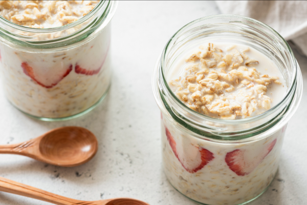 Two small mason jars full of overnight oatmeal, against a white background.