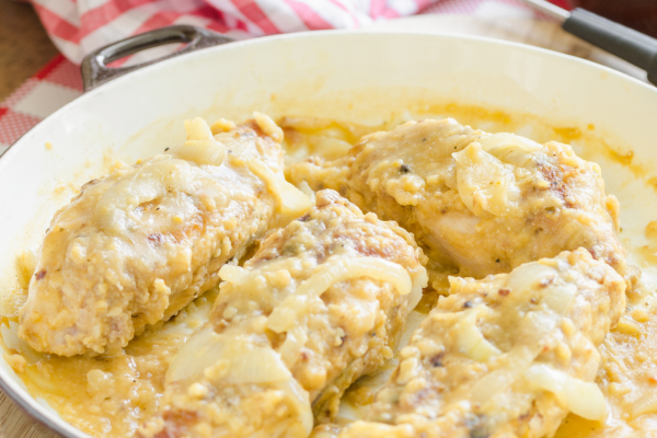 White pan full of smothered and covered chicken and gravy. Red plaid napkin is visible in the background.