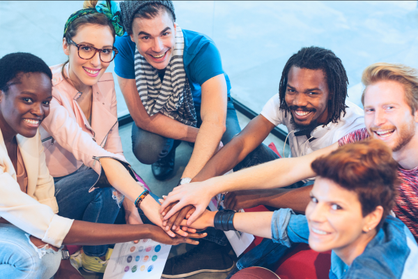 team of six people putting hands together 