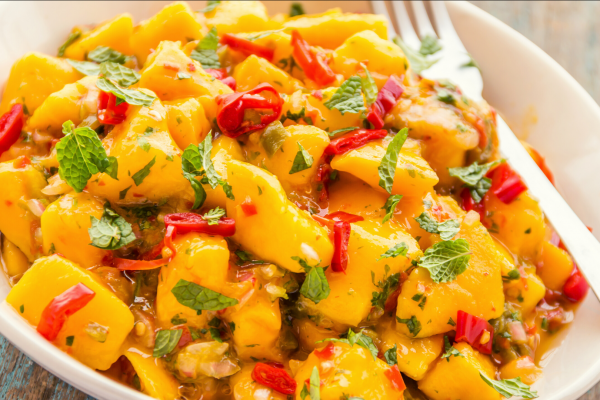 Tropical bean salad, with mango, pepper and tomato. Food is in a white bowl.