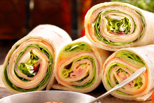 Four Turkey Tortilla Rollups stacked together in a sort of pile, on a cutting board.