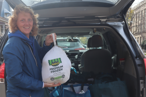 Woman holiday a frozen turkey outside her car with trunk open
