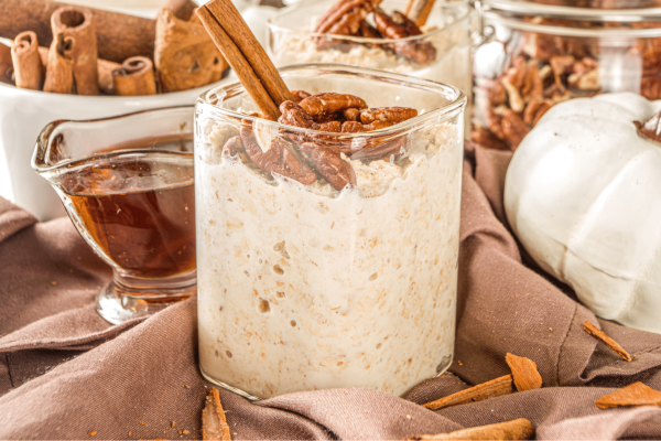 overnight oats with cinnamon and pecan garnish maple syrup in background