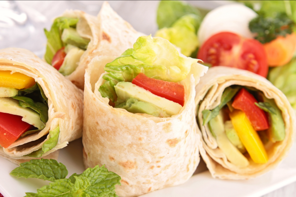 Closeup photo of small vegetable wraps on a white plate. 