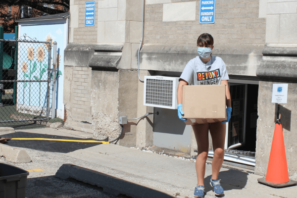 Beyond Hunger Volunteer carrying a box wearing a max for COVID-19