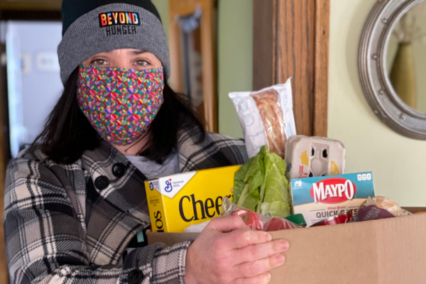 Woman in Beyond Hunger hat holding groceries